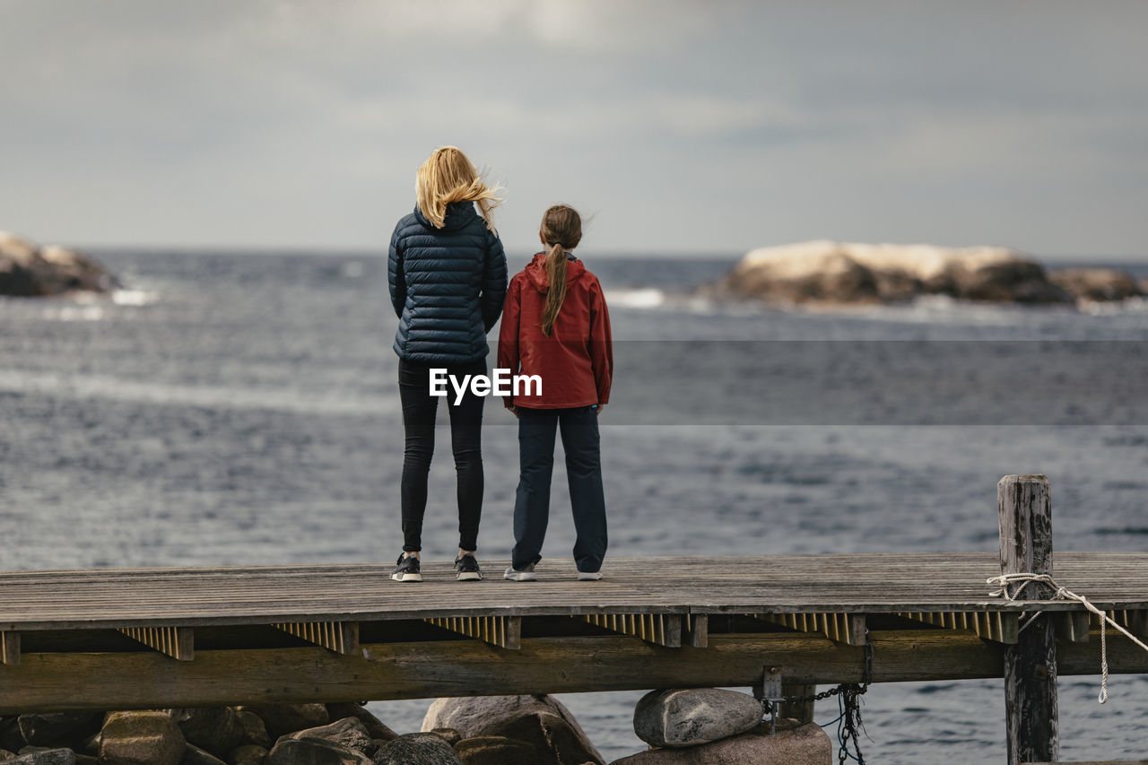 Mother and daughter standing on jetty