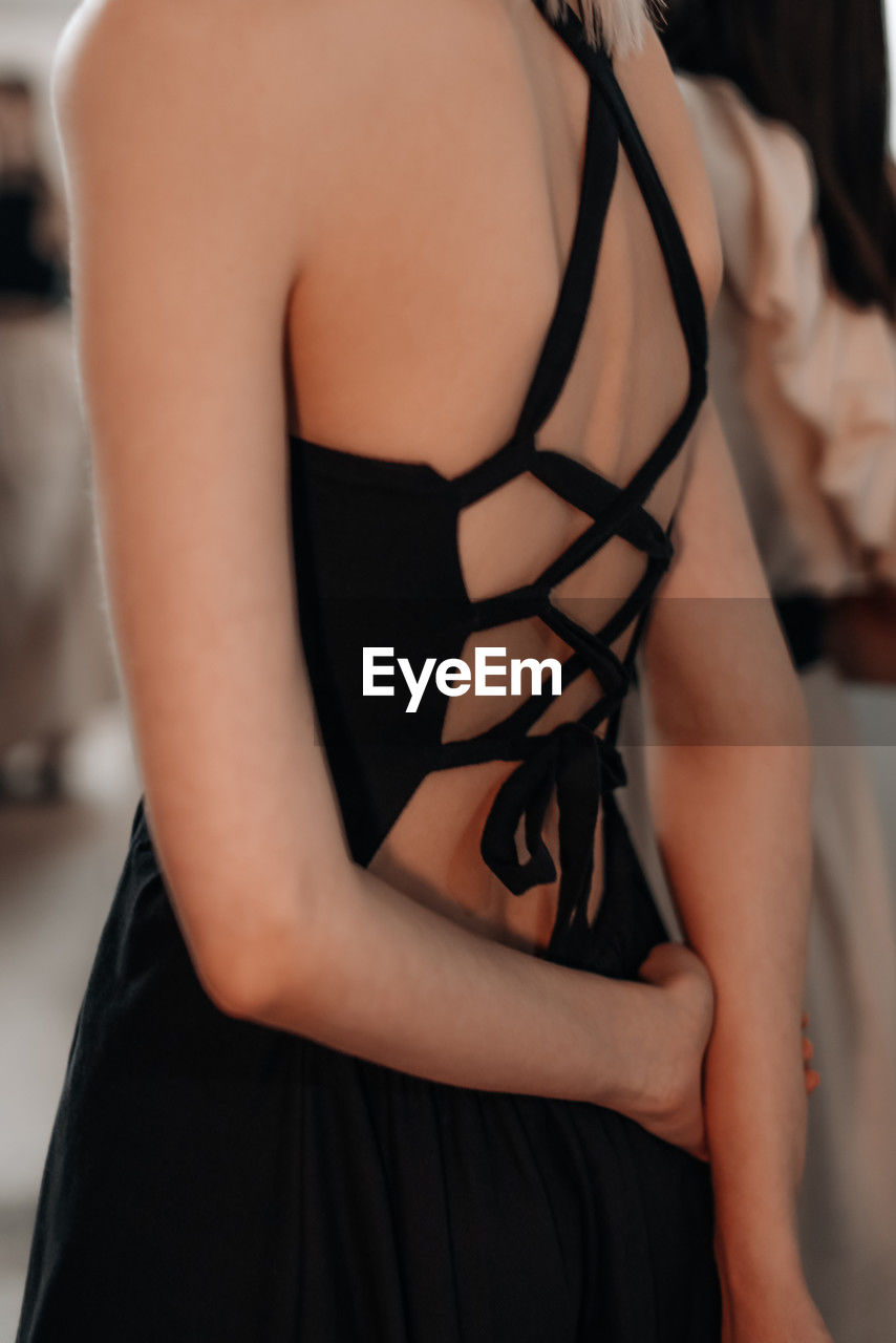Feminine fashion details of spring summer black elegant dress with lace up back. back view