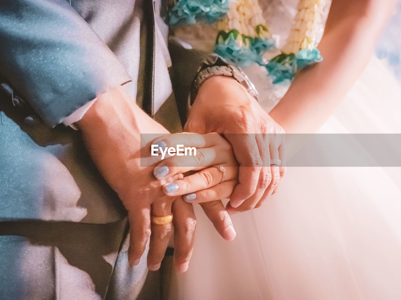 Midsection of couple holding hands at wedding