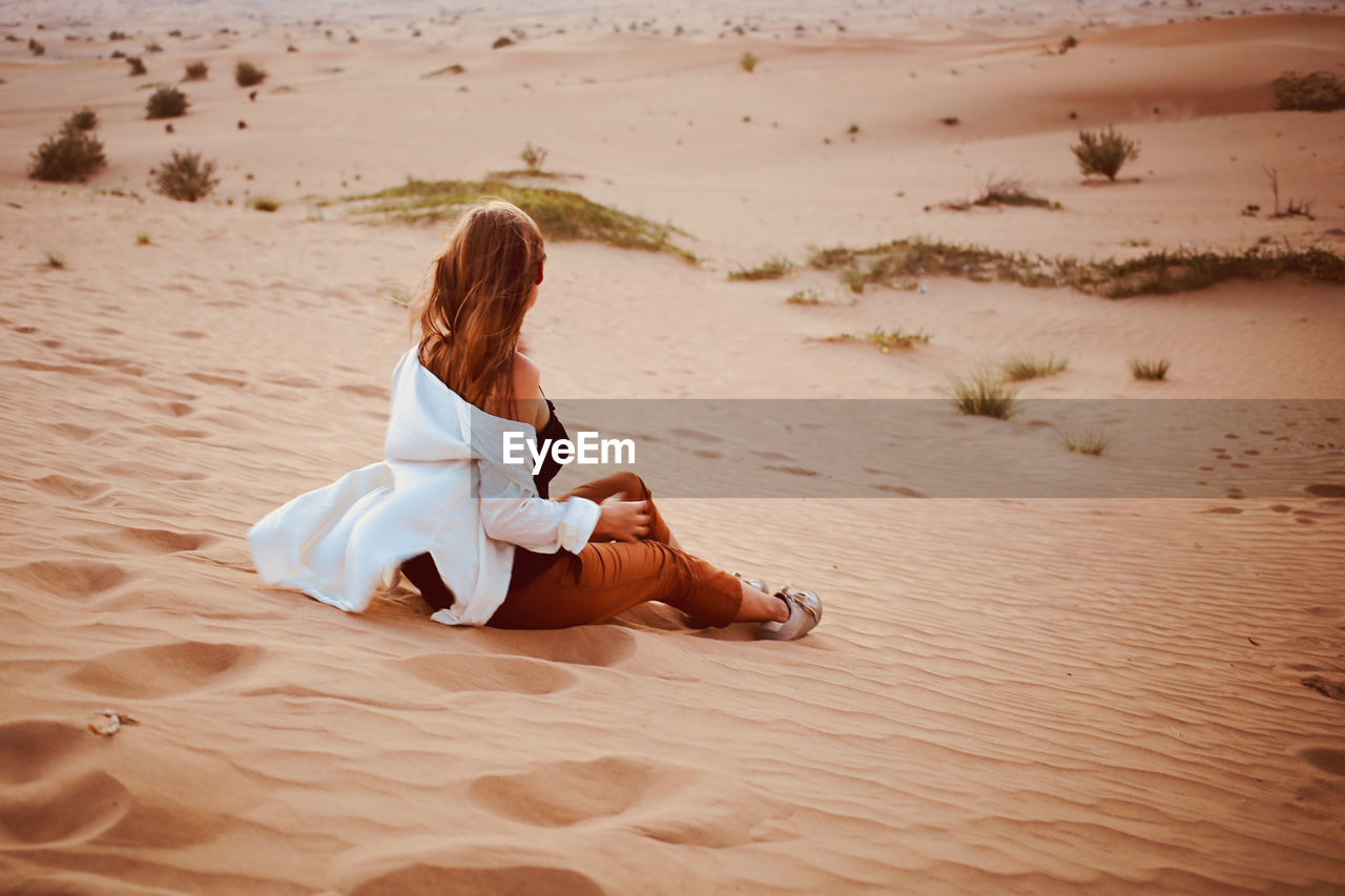 Woman sit back at desert sand