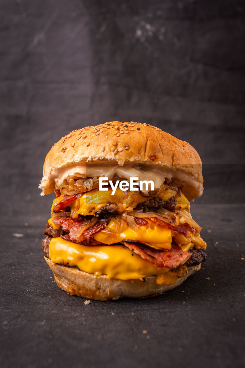 food and drink, food, sandwich, hamburger, fast food, studio shot, unhealthy eating, bread, meat, copy space, dish, freshness, meal, bun, cheese, dark, vegetable, indoors, yellow, no people, take out food, snack, rustic, produce, dairy, breakfast, fruit, black background, condiment, gourmet, red meat, wood, beef, onion, seed, single object