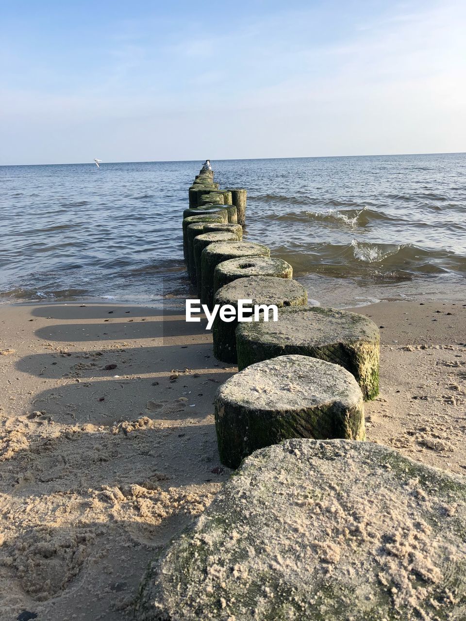 Stones on sea shore against sky