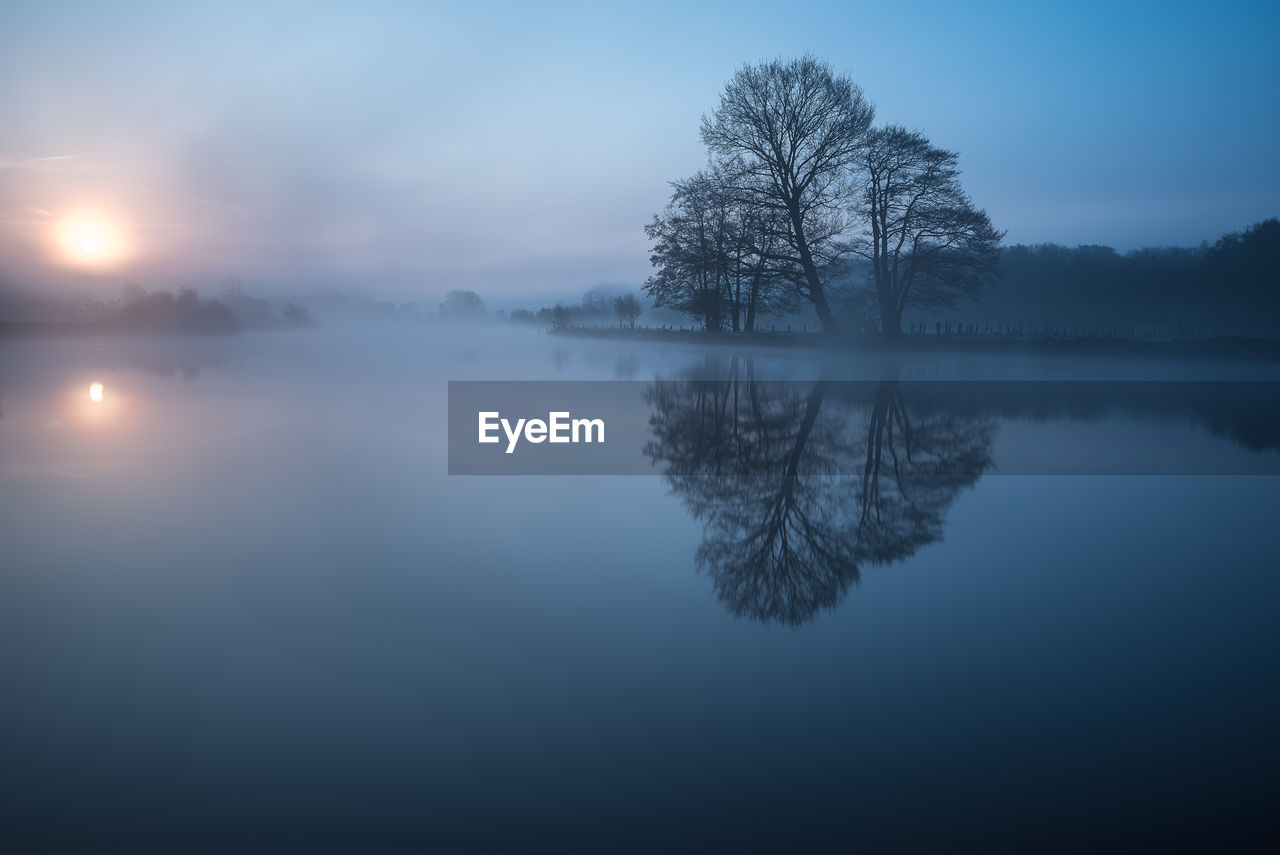 Scenic view of lake against sky during foggy weather