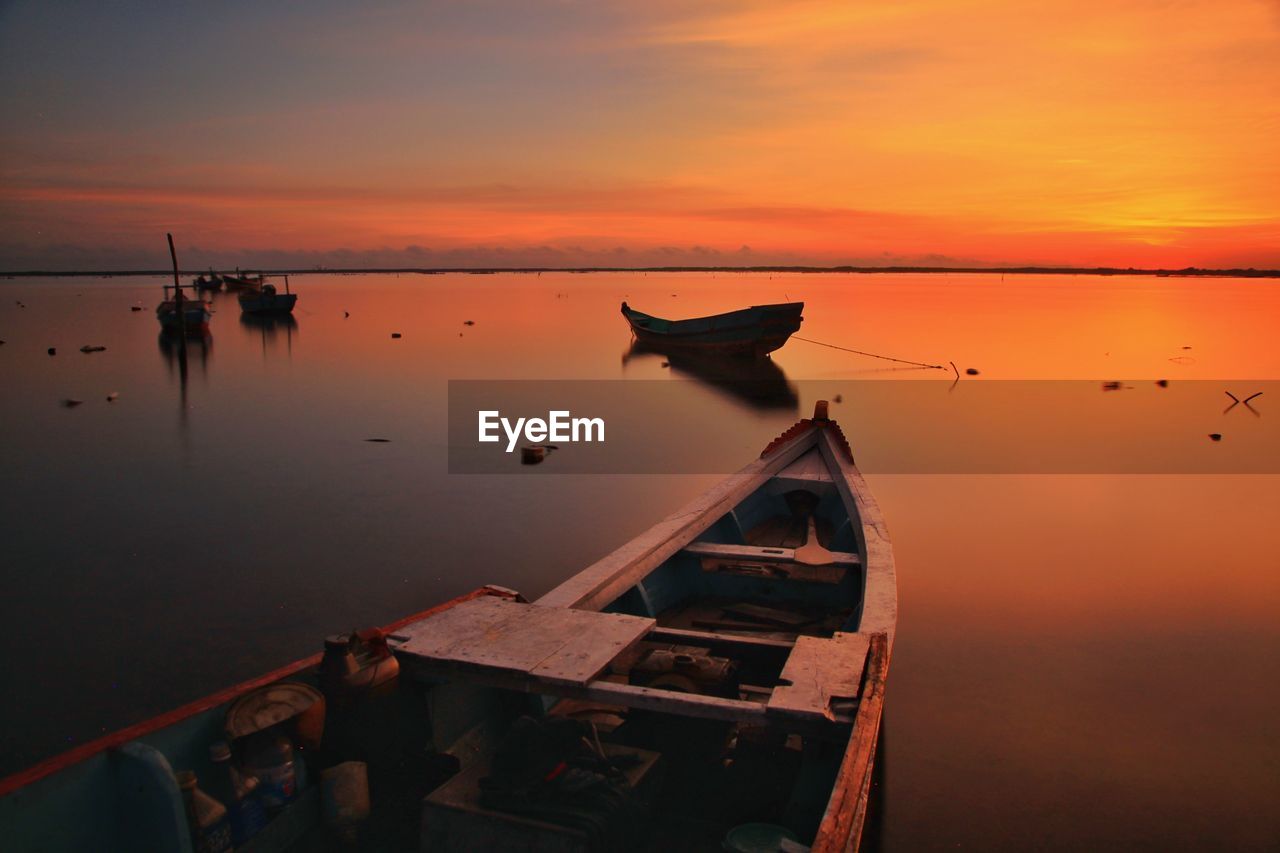 Boats moored on sea against sky during sunset