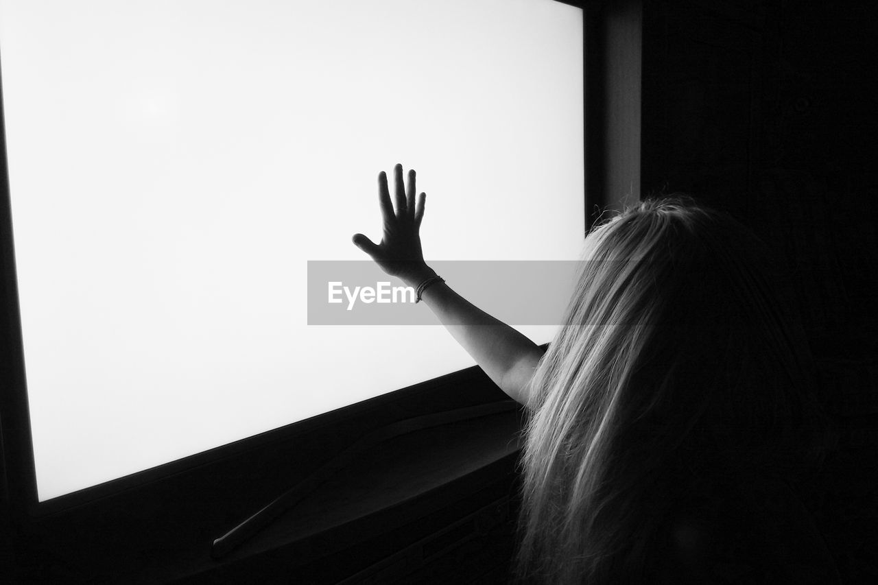 Close-up of girl with long hair touching television set