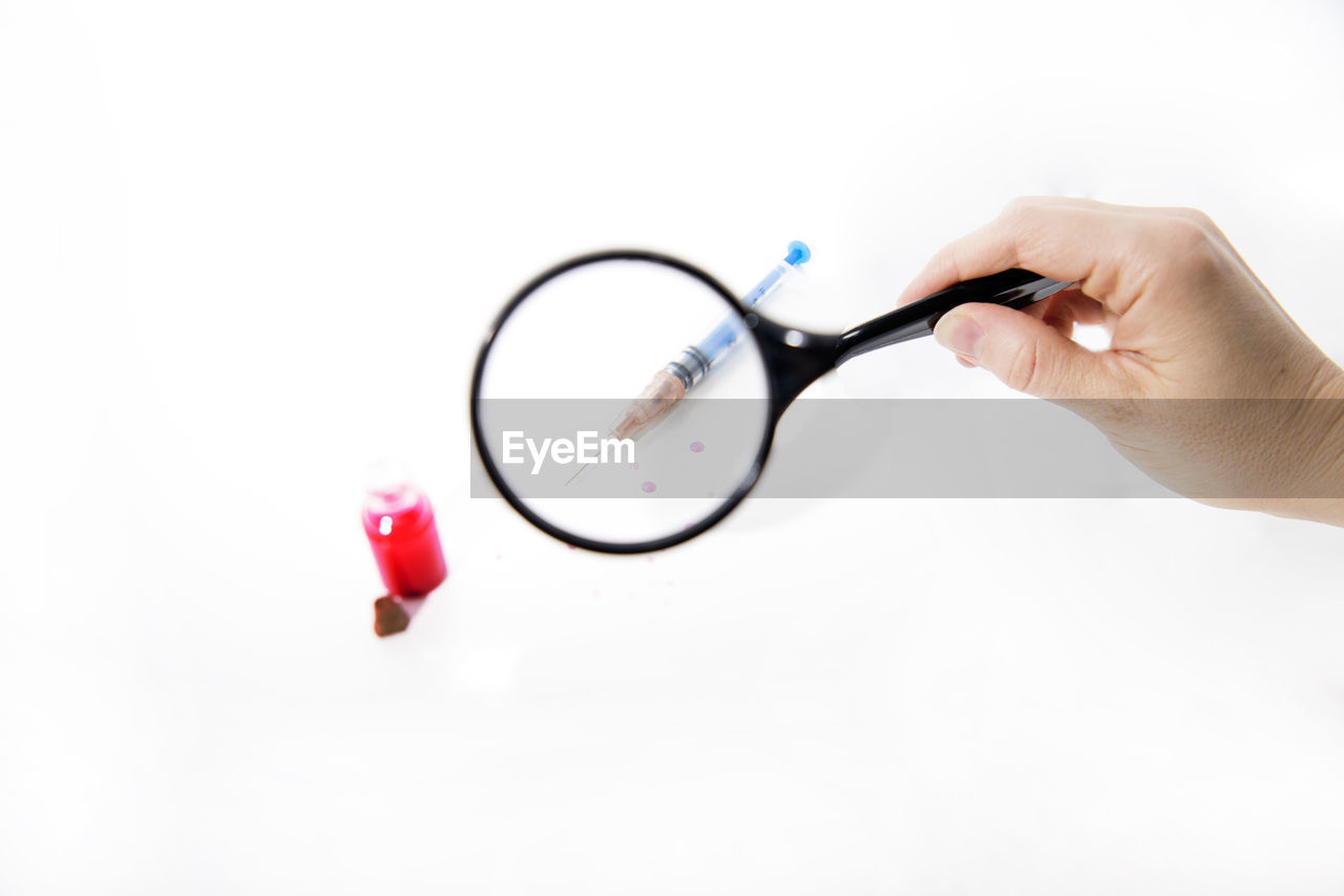 CLOSE-UP OF HAND HOLDING EYEGLASSES OVER WHITE BACKGROUND