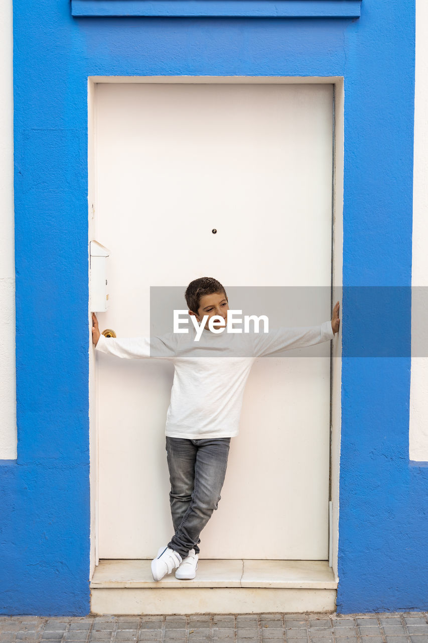 Little kid in front of a blue and white door