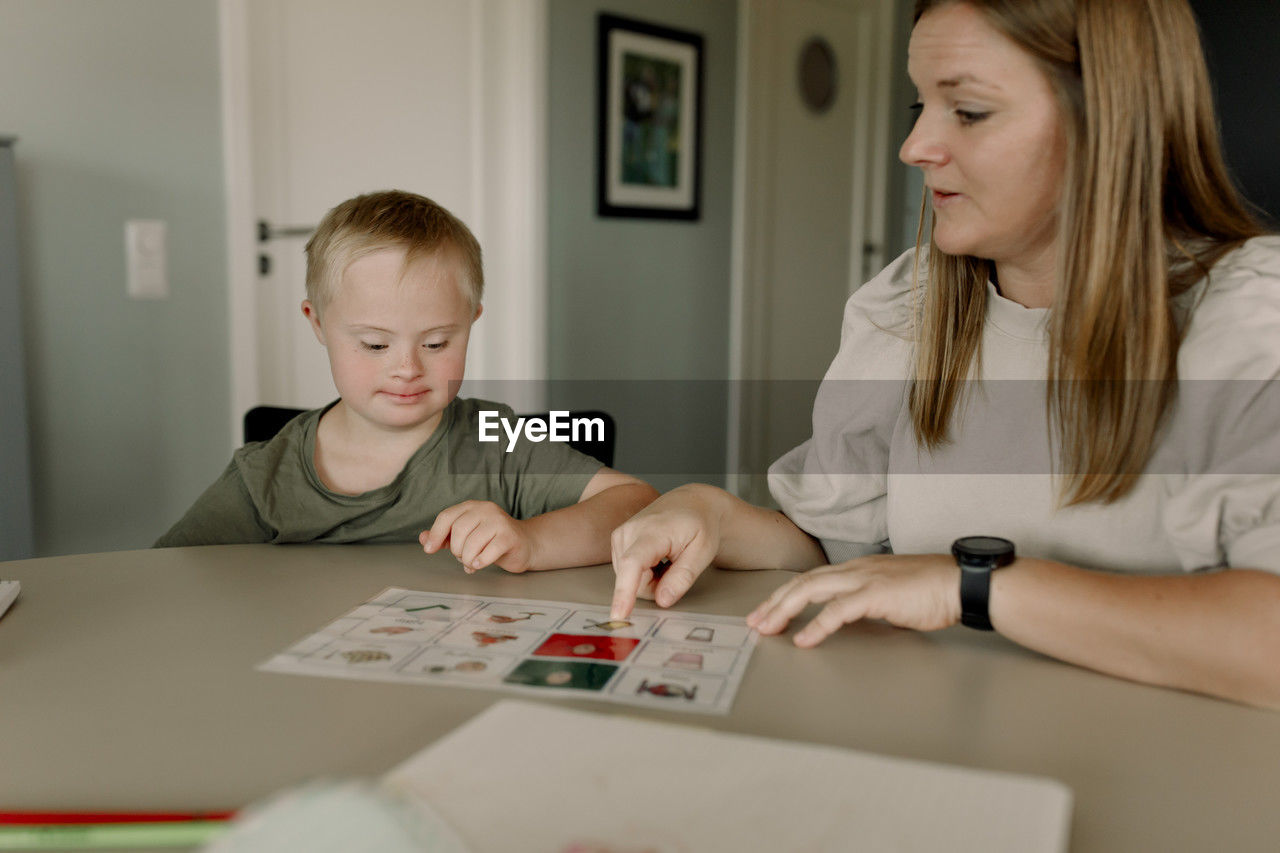 Mother teaching son with down syndrome at home