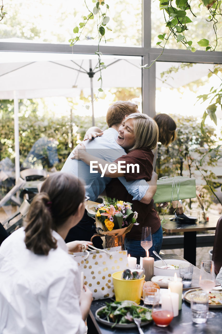 Happy parent embracing son during birthday party at restaurant