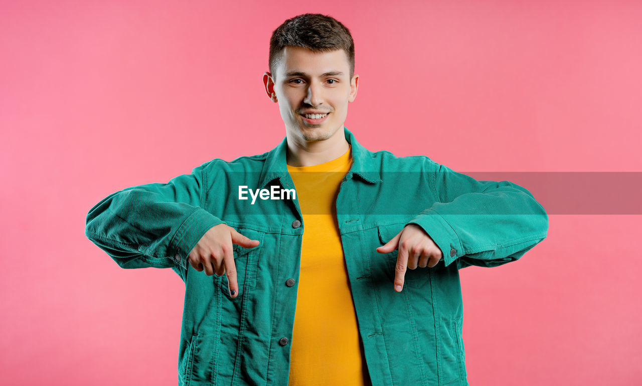 portrait, one person, studio shot, looking at camera, smiling, colored background, young adult, adult, happiness, outerwear, men, indoors, front view, emotion, standing, waist up, clothing, cheerful, green, sleeve, lifestyles, casual clothing, hood, positive emotion, copy space, teeth, person, smile, photo shoot, spring