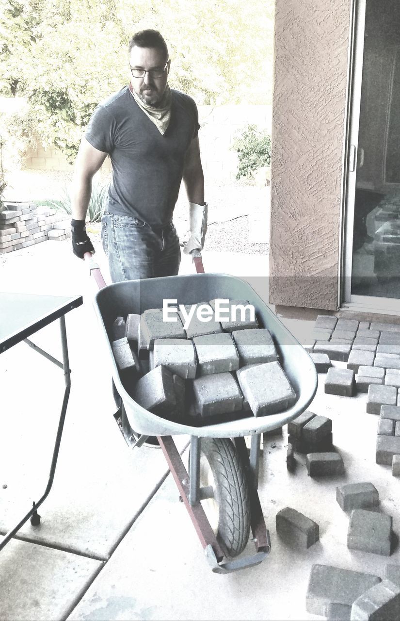 Manual worker carrying concrete blocks in wheelbarrow