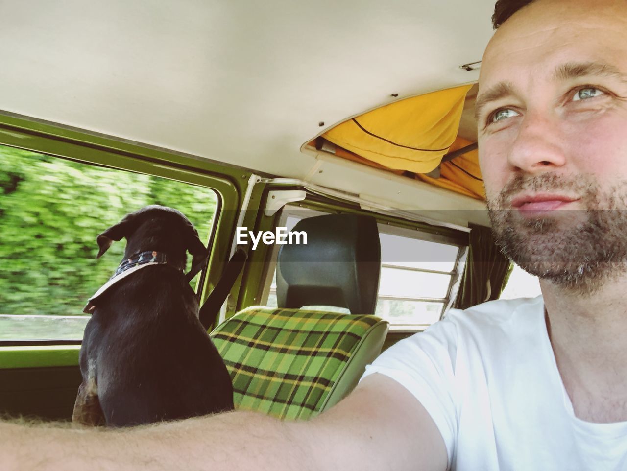 Man with dog sitting in car