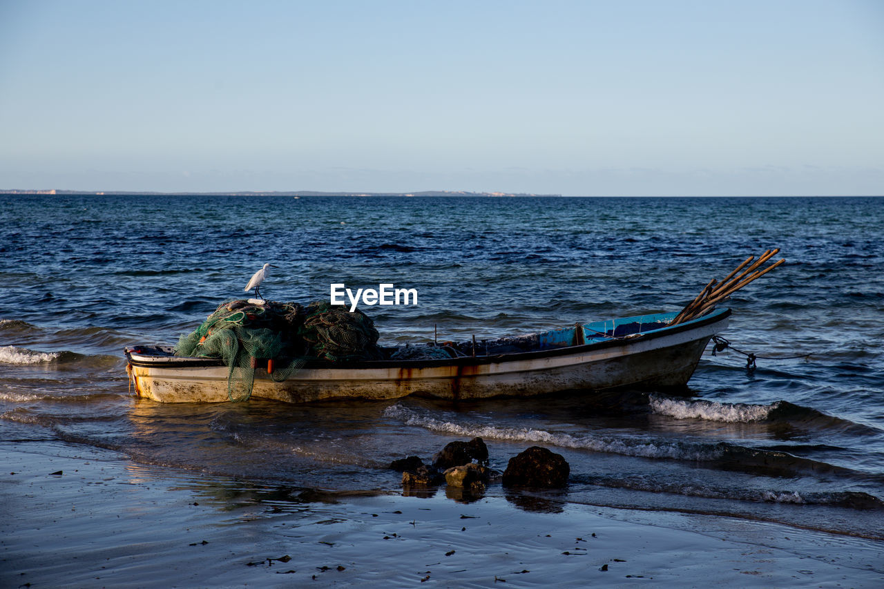 Boat moored on sea against clear sky