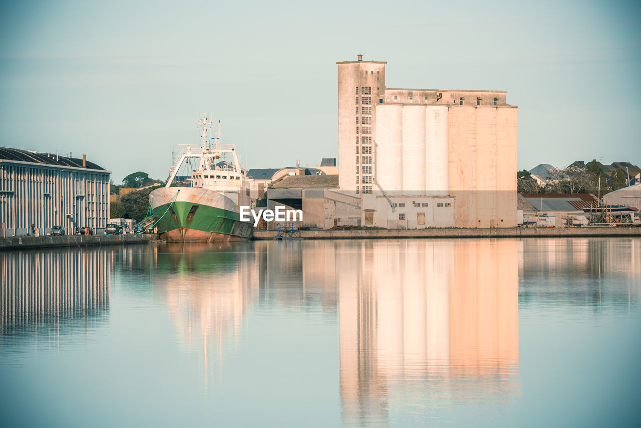 BUILDINGS BY RIVER AGAINST SKY