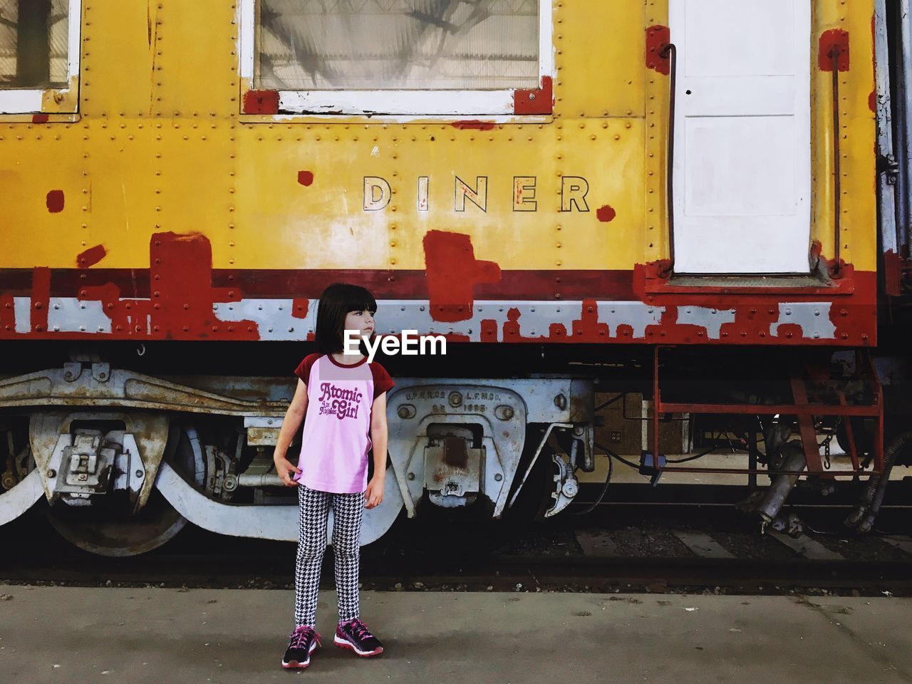 Full length of girl looking away while standing against train