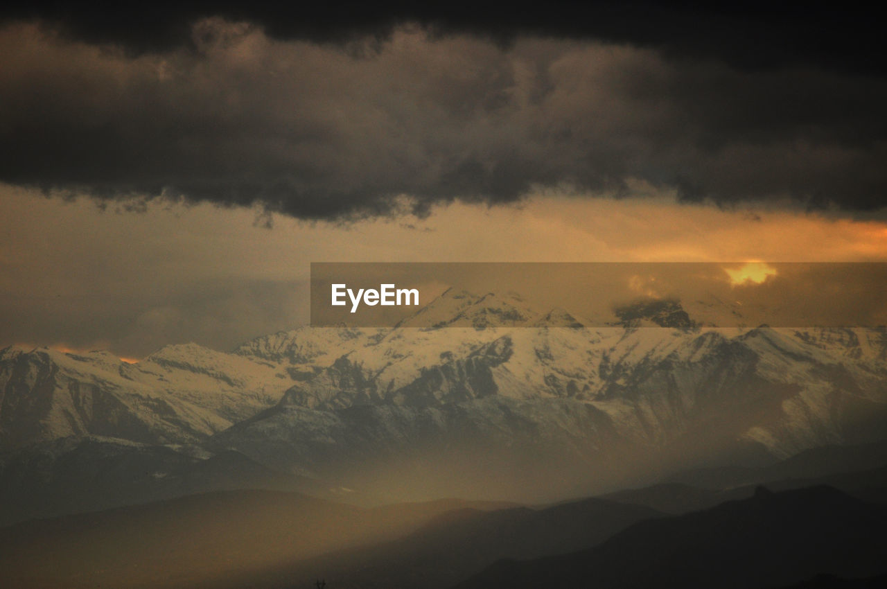 Scenic view of snowcapped mountains against dramatic sky