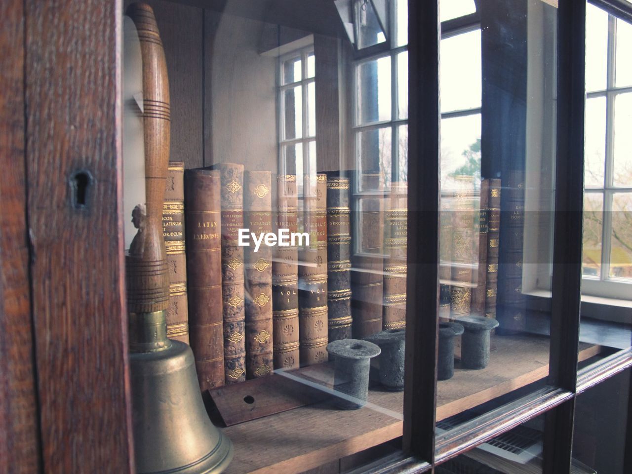 Books and bell on shelf in glass cabinet