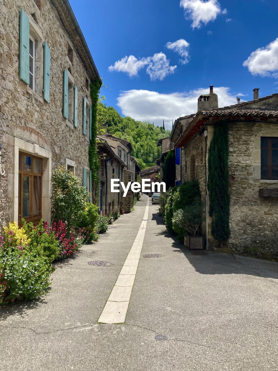 Empty road by buildings in town against sky