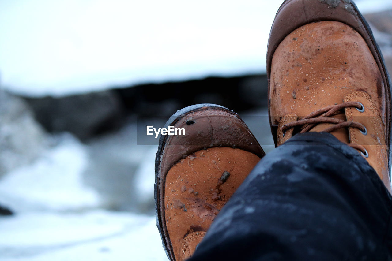 Low section of person wearing shoes on snow