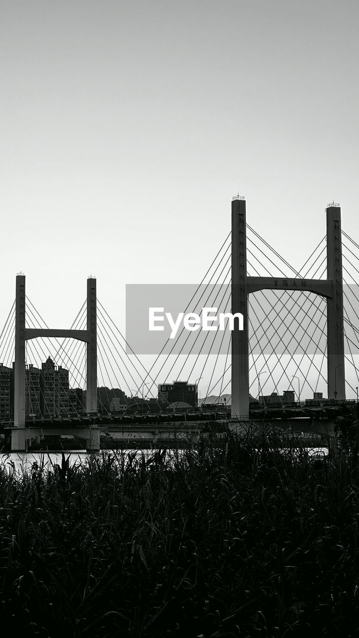 built structure, sky, architecture, bridge, black and white, suspension bridge, nature, travel destinations, transportation, monochrome photography, monochrome, engineering, travel, city, tourism, clear sky, landscape, copy space, skyline, outdoors, building exterior, plant, water, horizon, line, day, cable-stayed bridge, urban skyline, cityscape