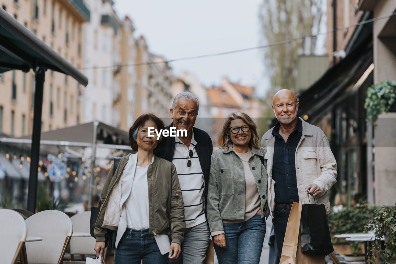 Portrait of male and female senior friends walking at sidewalk