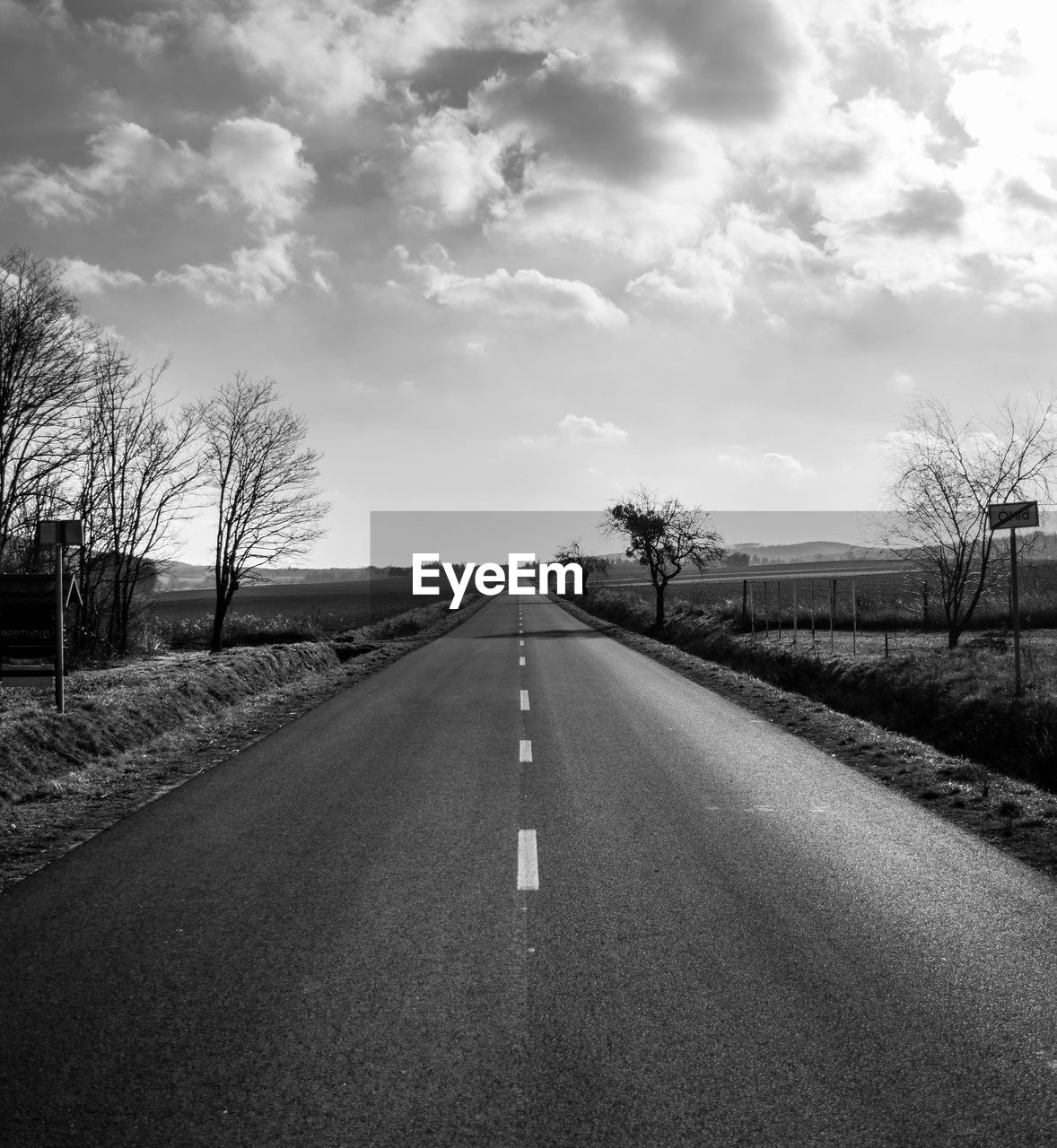 EMPTY ROAD WITH TREES IN BACKGROUND