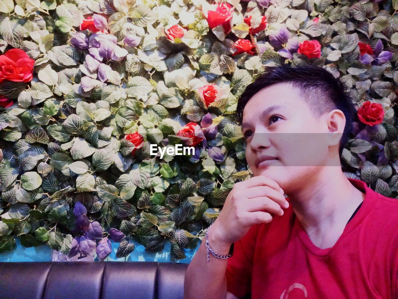 PORTRAIT OF WOMAN LOOKING AT RED FLOWERING PLANT