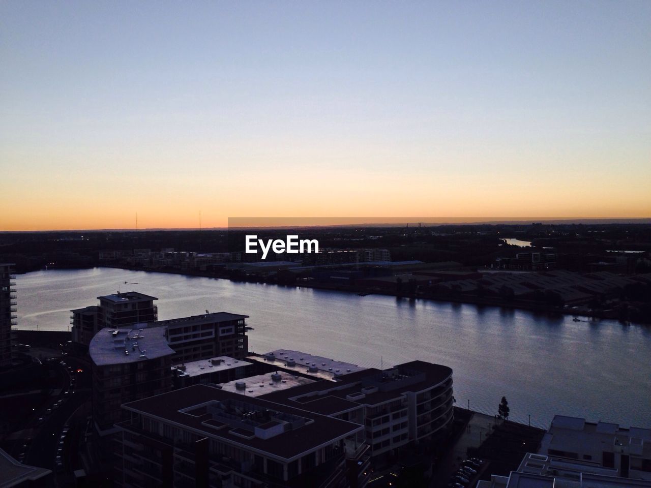 High angle view of houses by river during sunset