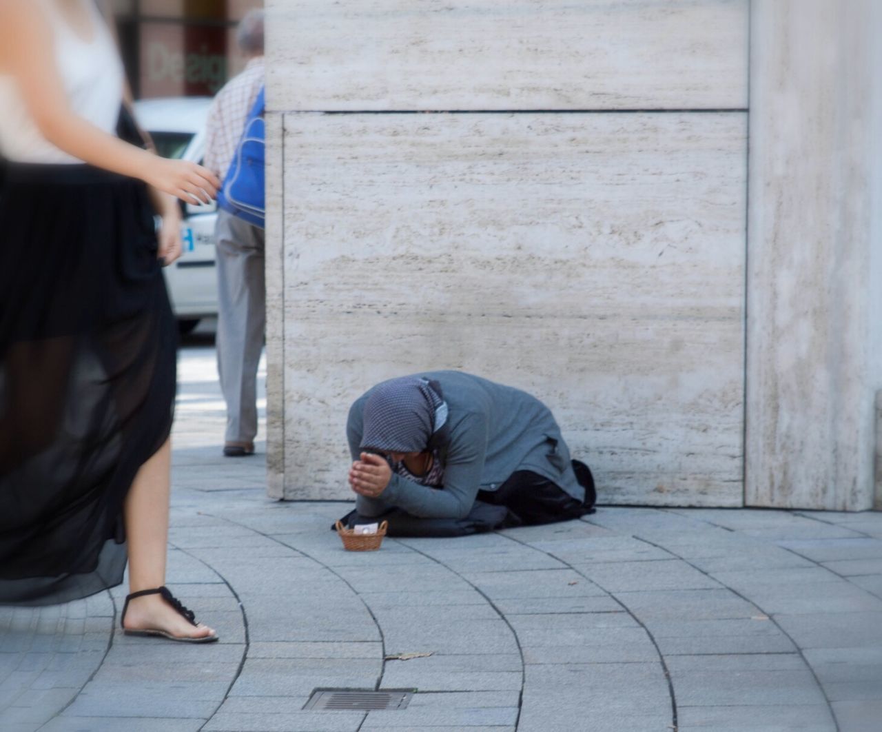 Woman walking by beggar on sidewalk