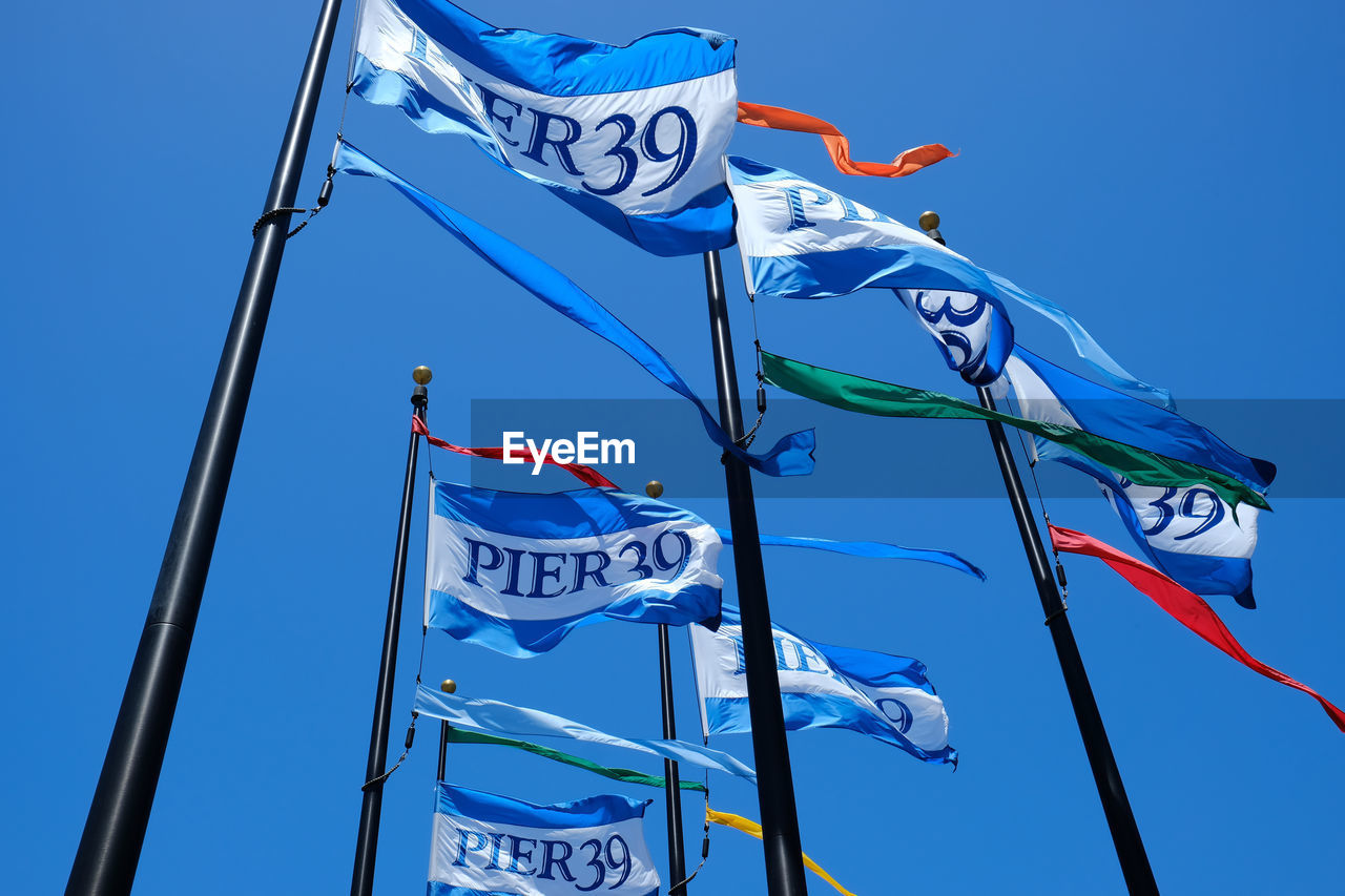 Low angle view of flags against blue sky