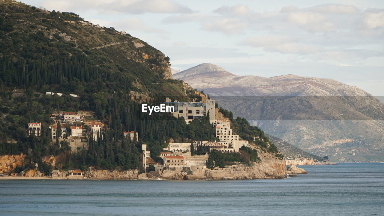 Scenic view of sea by townscape against sky