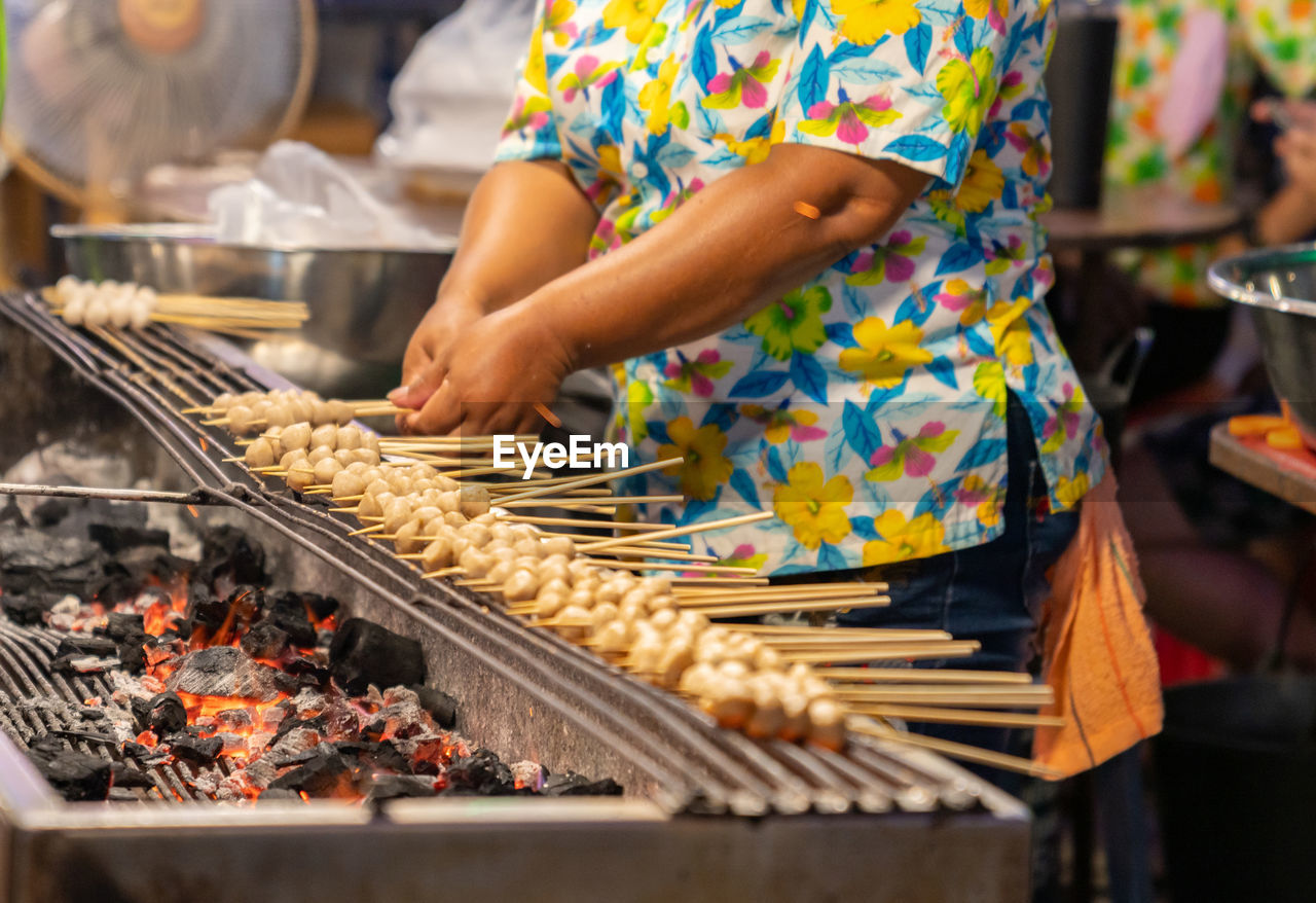 Woman grilling the meat ball with chracoal in street food market.