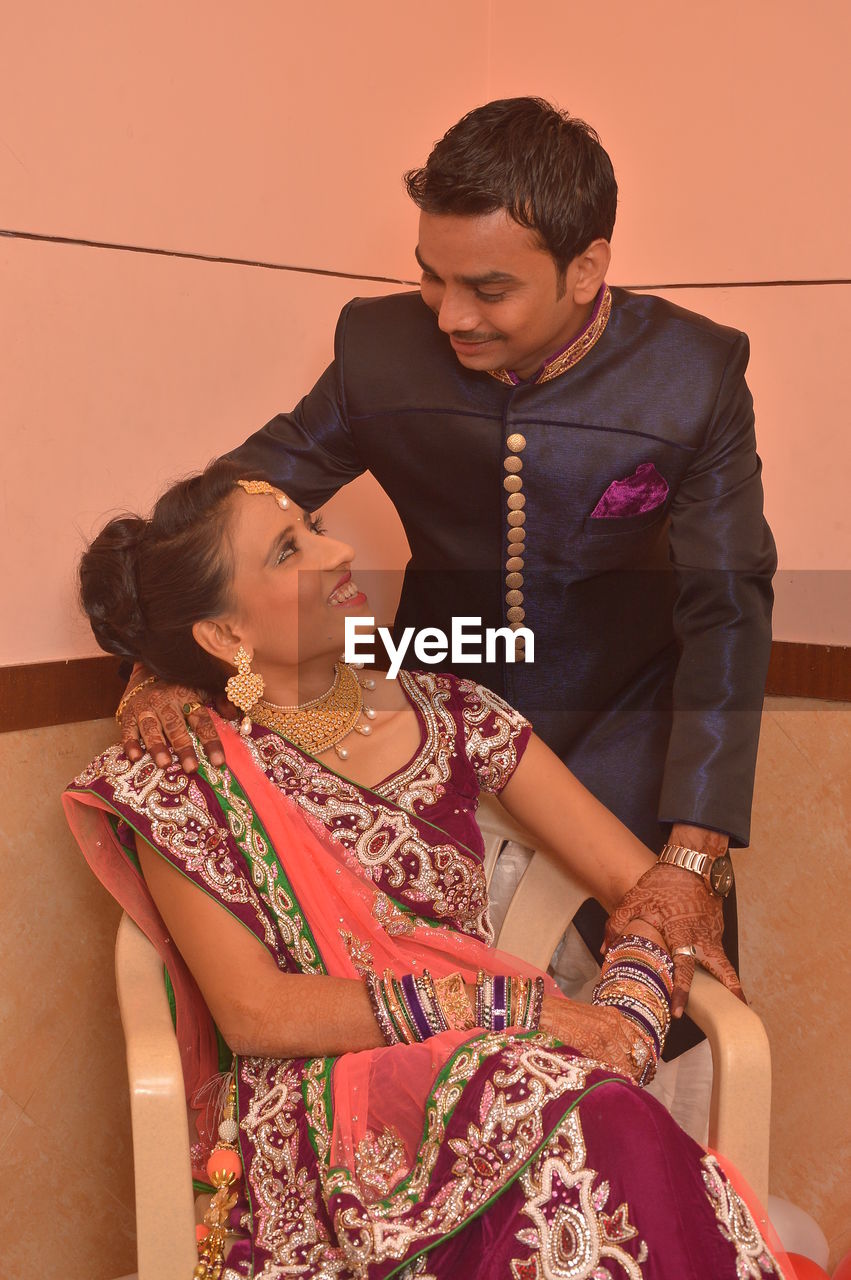 Smiling young couple looking at each other against wall