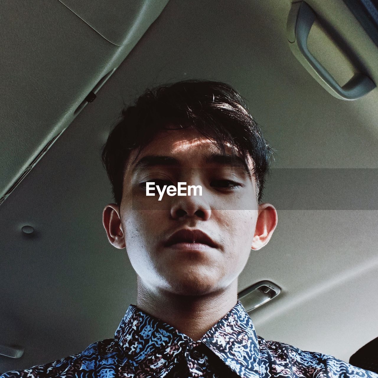 LOW ANGLE PORTRAIT OF YOUNG MAN IN BUS