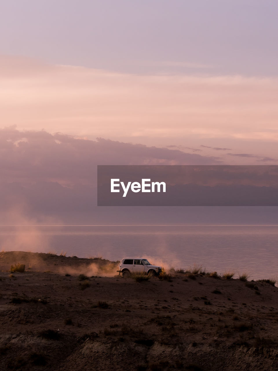 Vehicle on field against sky during sunset