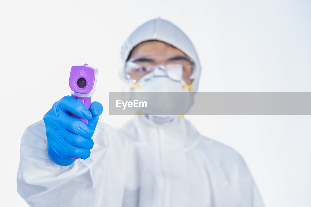 Portrait of boy wearing protective suit holding infrared thermometer