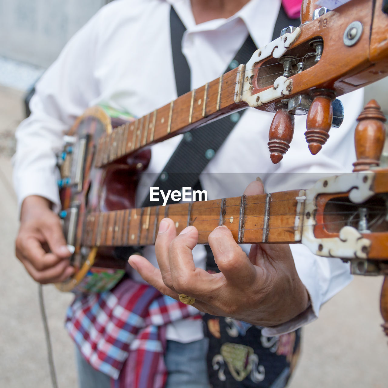 Midsection of man playing string instrument outdoors