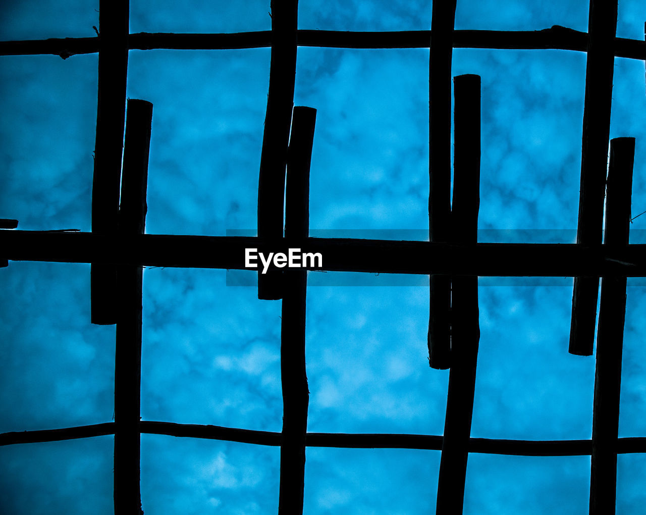 Low angle view of silhouette wooden structure against cloudy sky