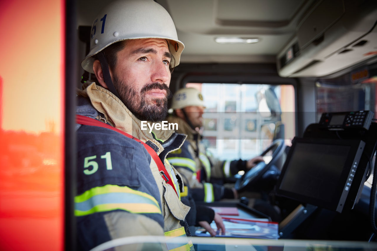 Firefighter looking through window while sitting in fire truck