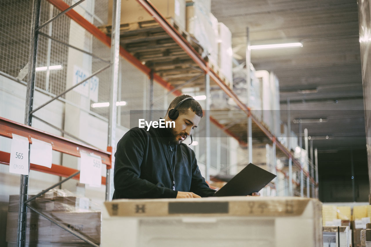 Male manual worker reading document at logistics warehouse