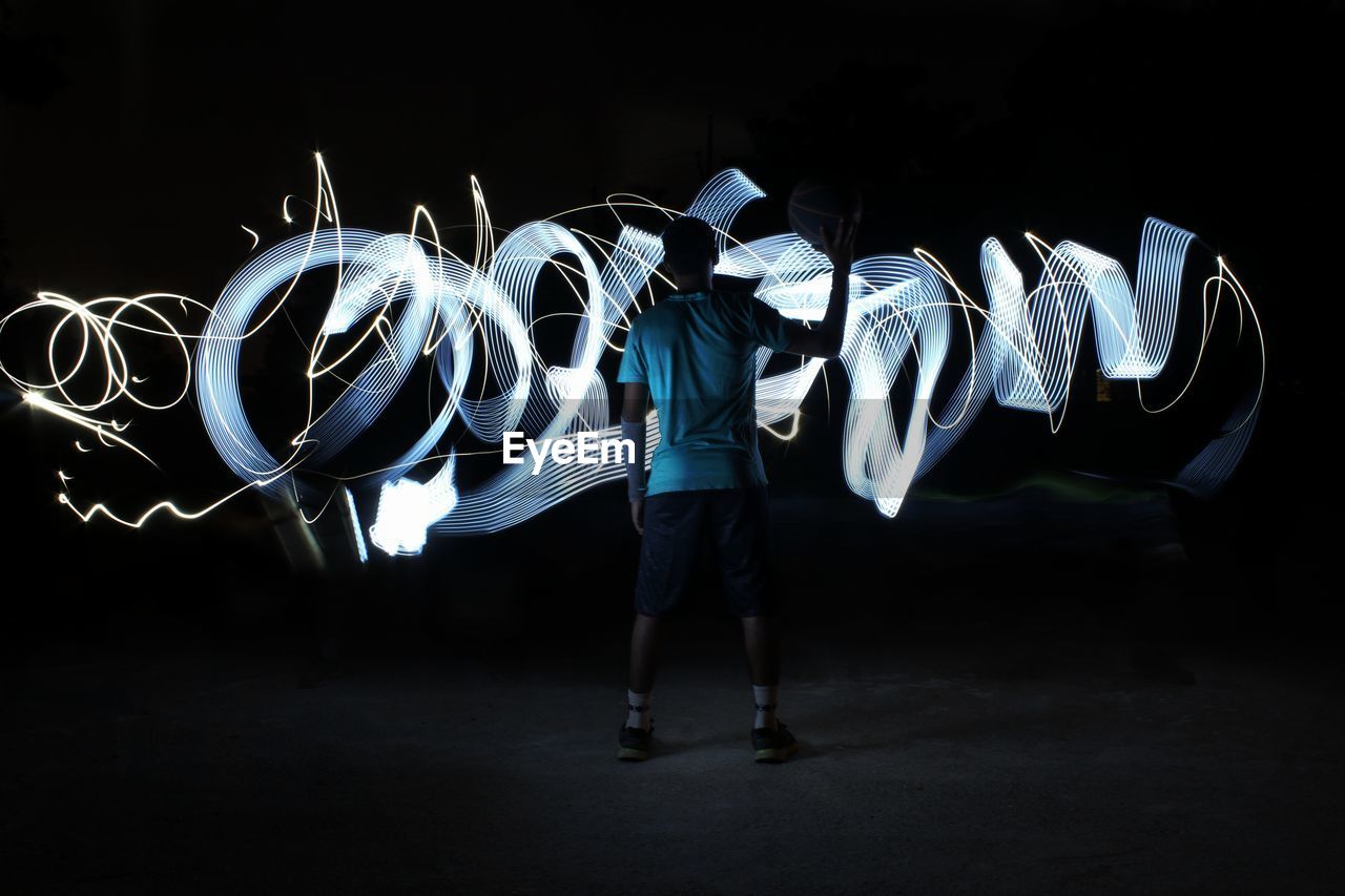 Rear view of man standing by light painting at night