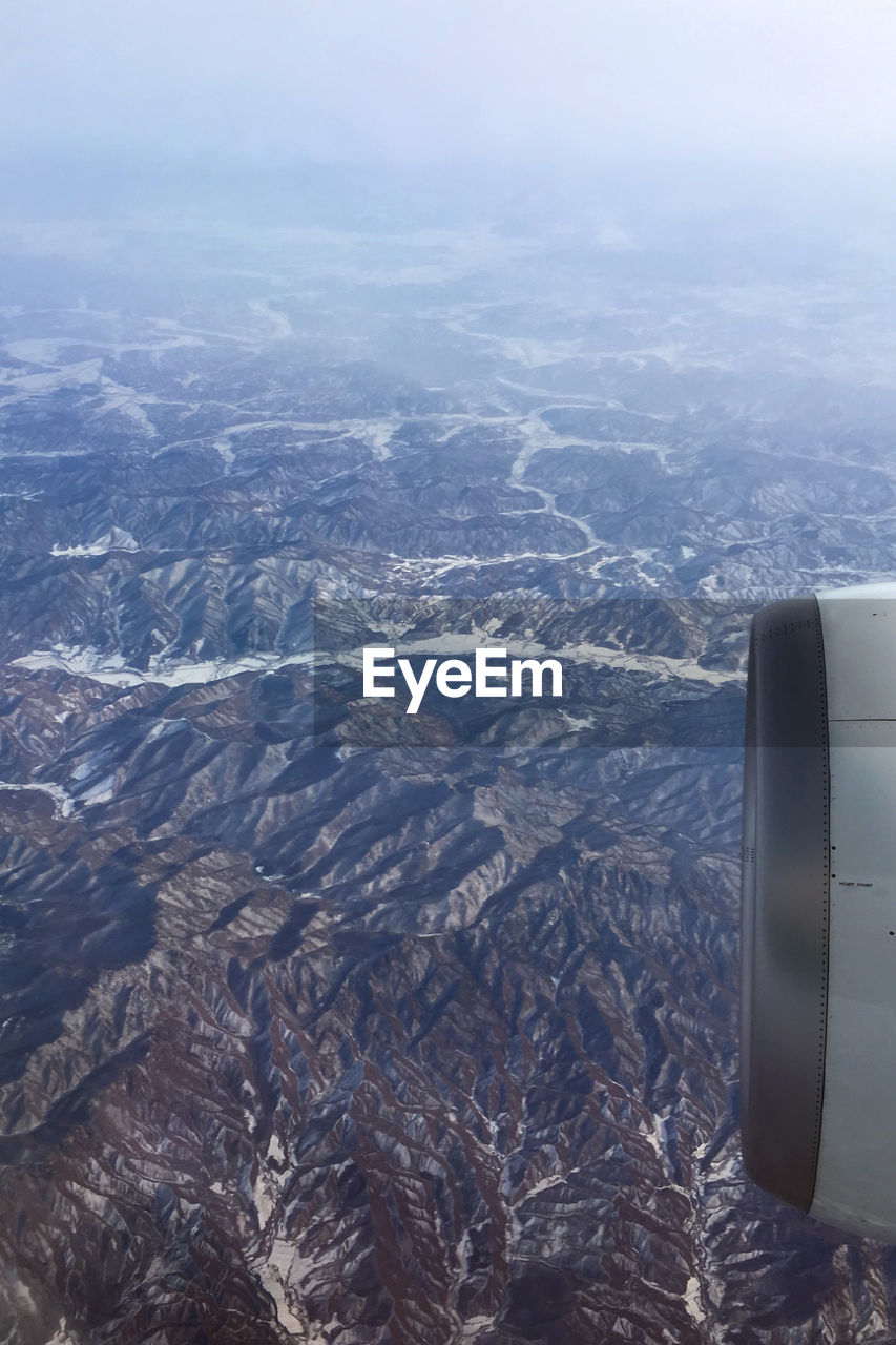 Cropped jet engine flying above mountains