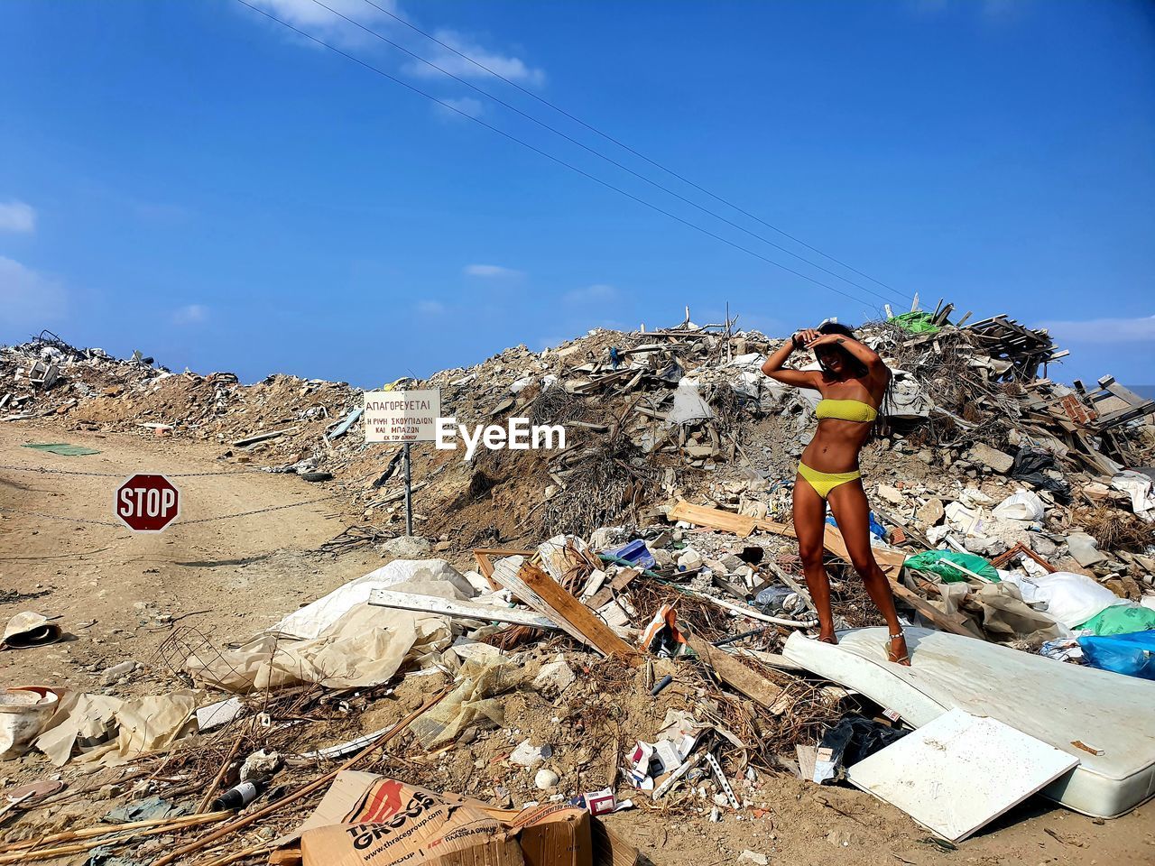 Woman in bikini standing on dumpster 