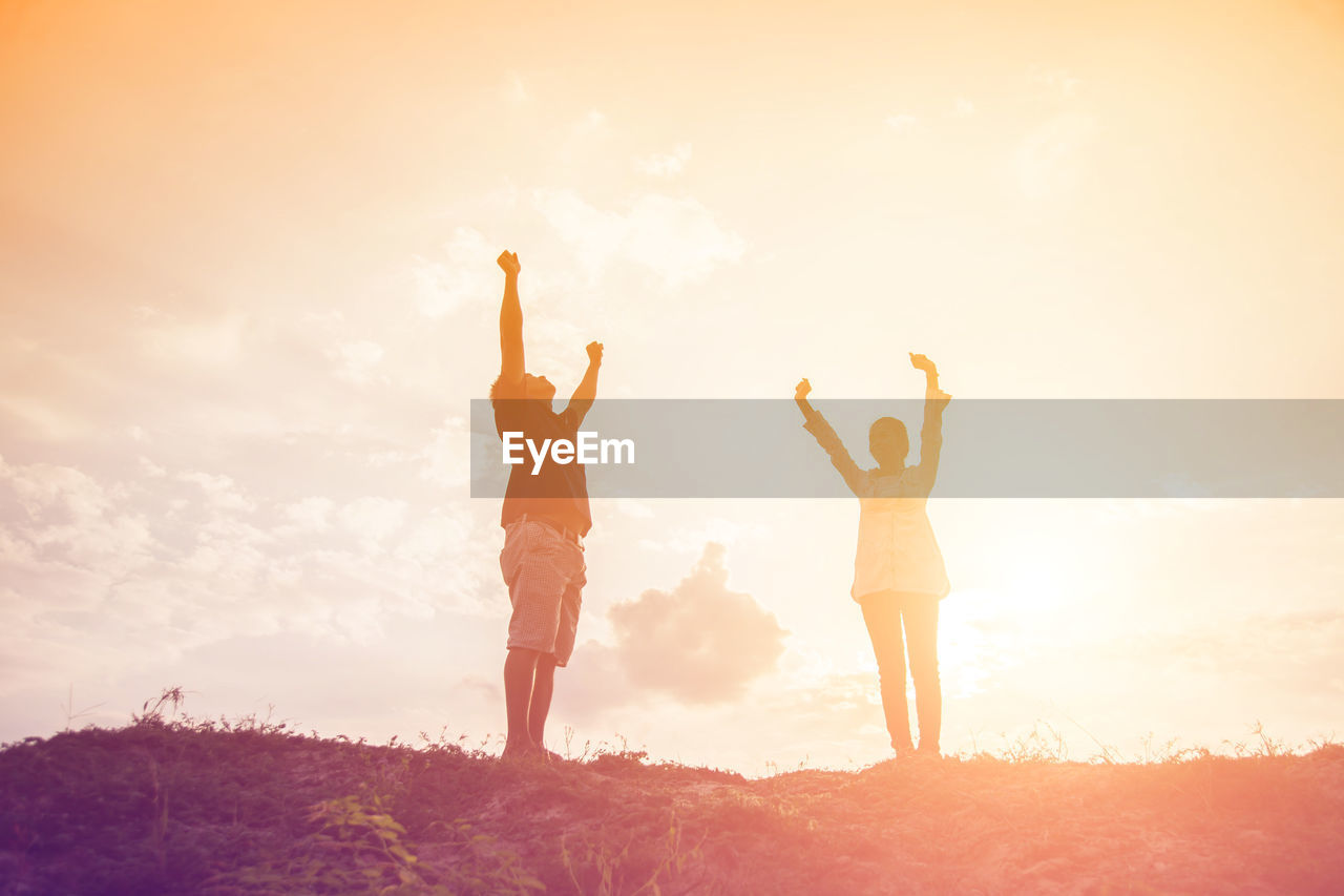 LOW ANGLE VIEW OF WOMEN STANDING ON LAND DURING SUNSET