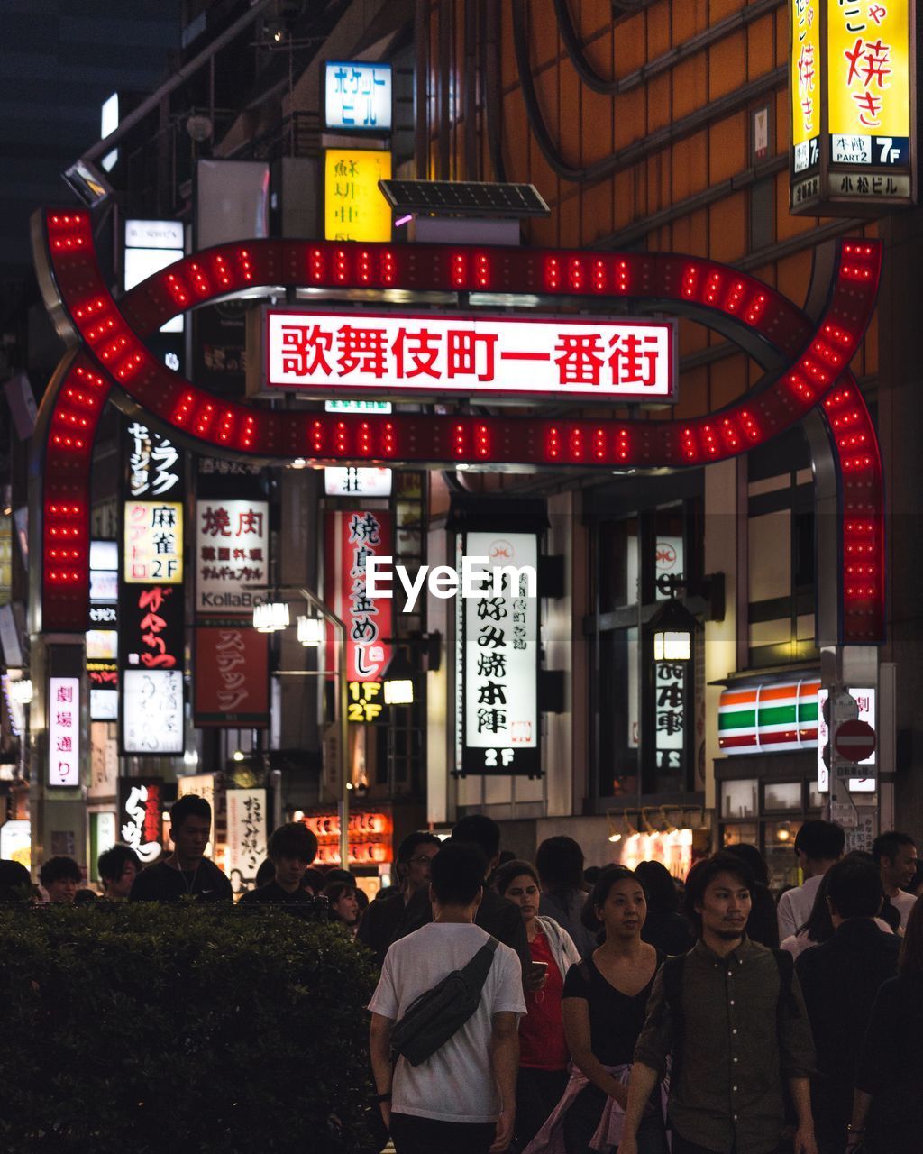 GROUP OF PEOPLE IN FRONT OF ILLUMINATED BUILDING