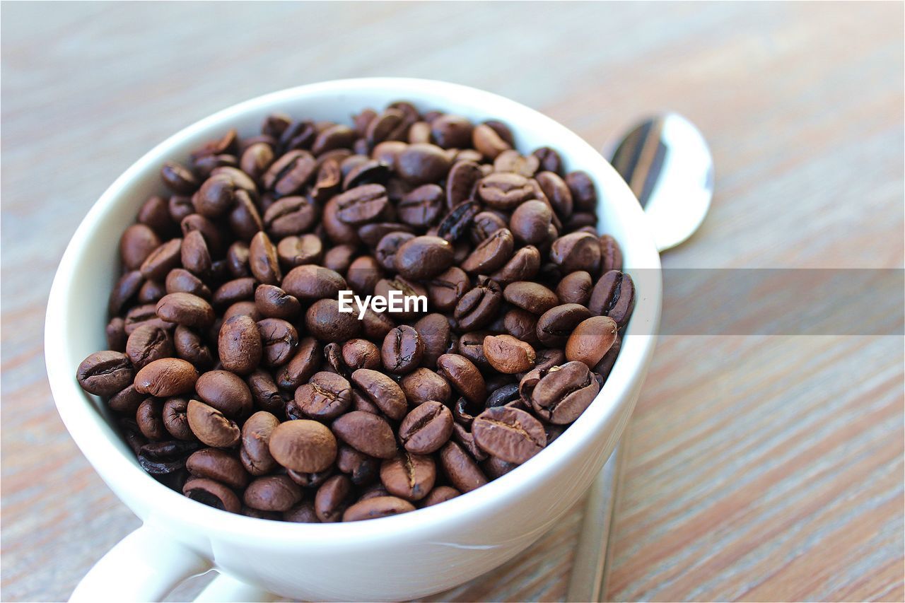 Close-up of roasted coffee beans in cup on table