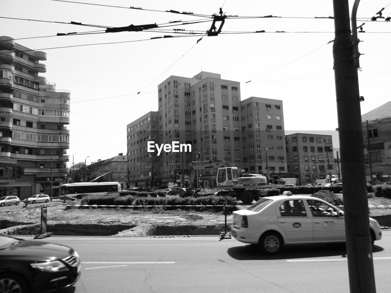 TRAFFIC ON ROAD BY BUILDINGS IN CITY