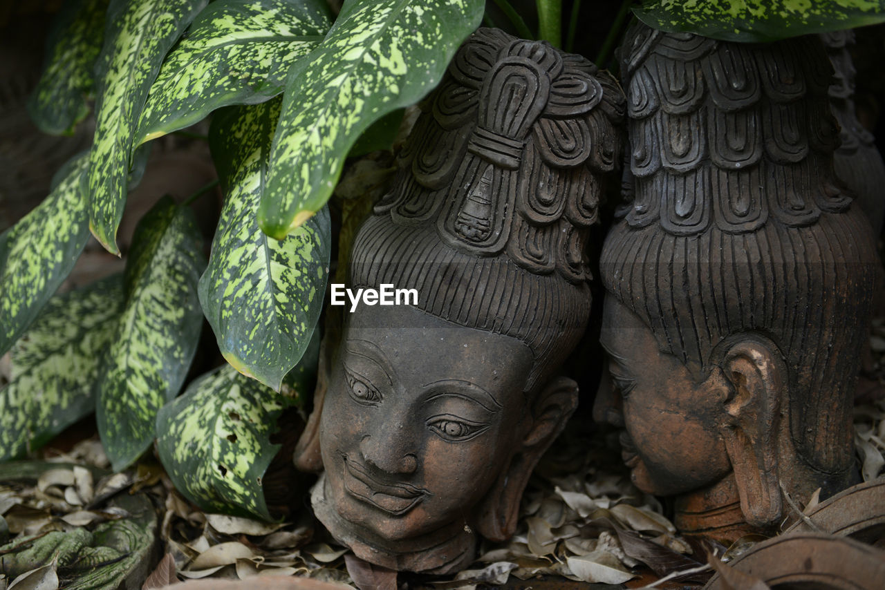 Close-up of abandoned statue by leaves