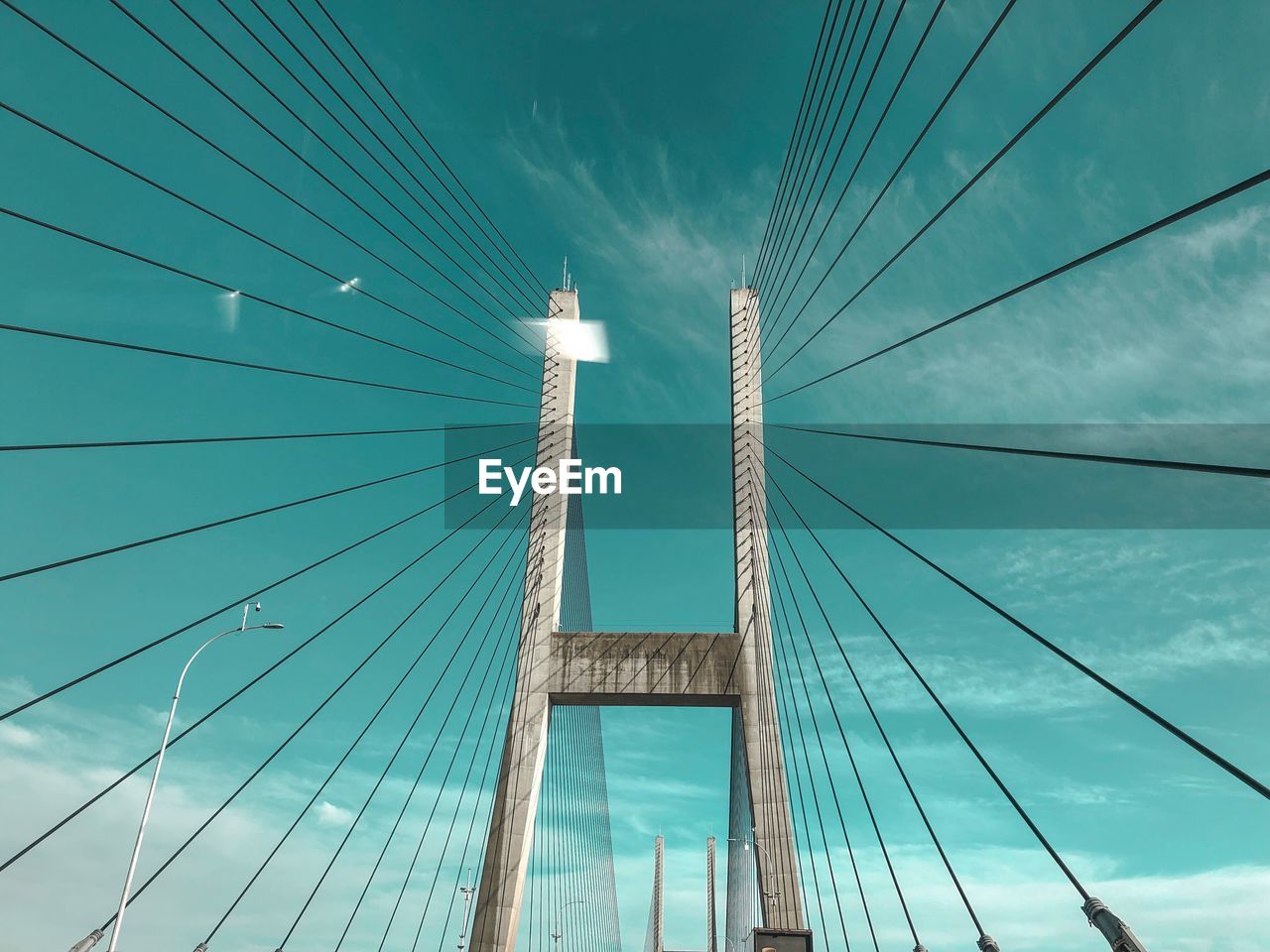 Low angle view of suspension bridge against cloudy sky