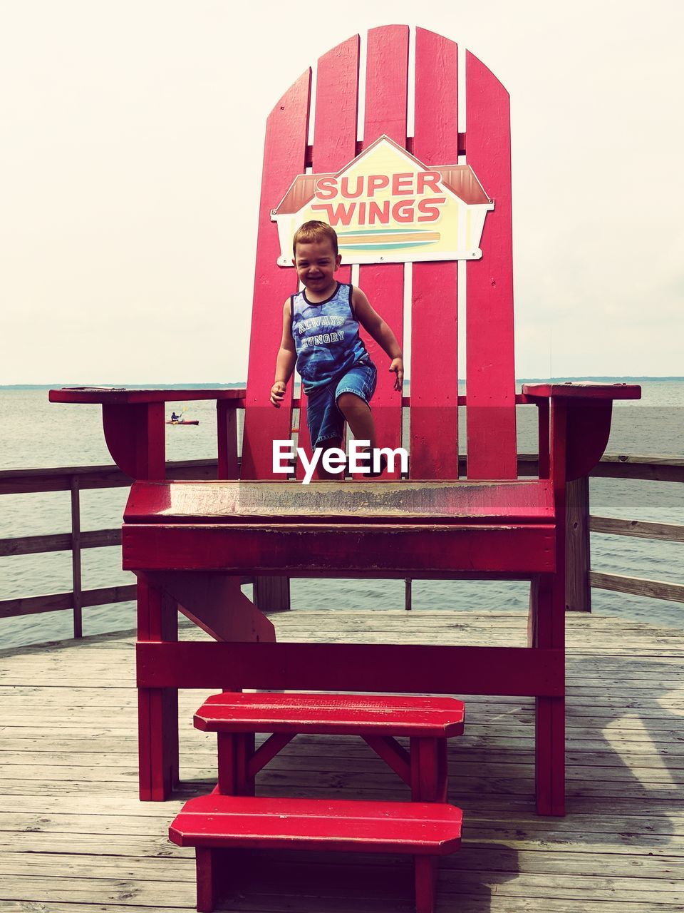 Full length of boy standing on chair at beach